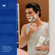 Shave cream tube held in hand with shaving foam on face