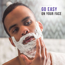 Shaving foam on a man’s face as hands smooth lather