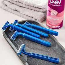 Blue disposable twin-blade razors with long handles on a tray