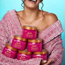 Person holding multiple Tree Hut Raspberry Fizz sugar scrub jars with orange lids
