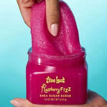 Hand scooping bright pink Tree Hut Raspberry Fizz sugar scrub from jar