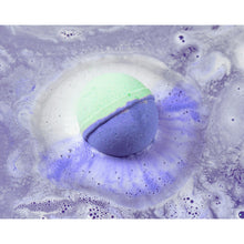 Bath bomb dissolving in water, purple and turquoise soap pieces