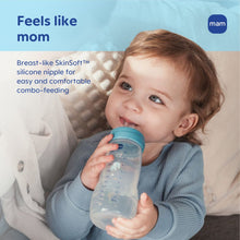 Toddler holding MAM Easy Active baby bottle with clear body and silicone nipple