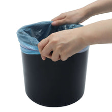 Black plastic bathroom step trash can with hands holding a liner bag