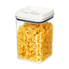 Clear square food container with white flip lid, filled with bright yellow corn snacks