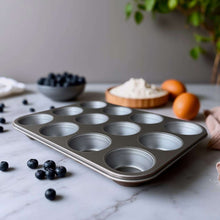 Gray nonstick muffin pan with 12 round cups, long edge close-up
