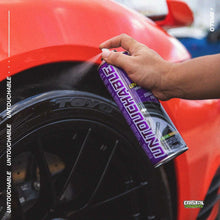 Wet tire finish spray can in hand near dark tire on red vehicle