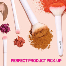 Makeup brush set with plush bristles and scattered brown, pink, and red eyeshadow