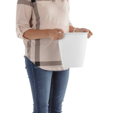 White plastic trash can held by a person, open top, no lid.