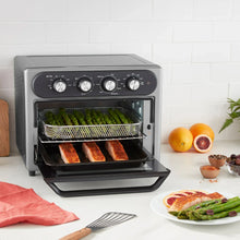Gray air fryer oven with basket inside and cooked food, front control panel visible