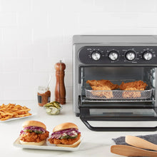 Gray air fryer oven with basket inside, closed glass door and front control dials