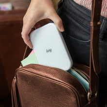 White mini photo printer in hand, showing front panel