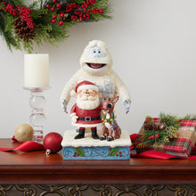 Jim Shore holiday statue of Rudolph, Bumble, and Santa on a blue decorated base