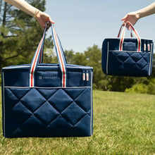 Quilted blue cooler bag set held by striped handles, showing large and small sizes