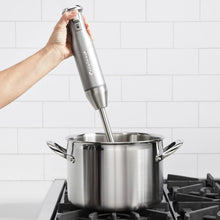 Handheld immersion blender blending into a stainless steel pot