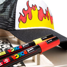 Close-up of POSCA markers in red and black near a decorated surface
