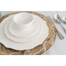 Stack of white porcelain side plates with embossed dahlia floral border