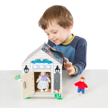 Wooden dollhouse toy with open doorway and child holding poseable dolls