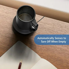 Warming coffee mug on heated coaster with lid and side handle on tabletop