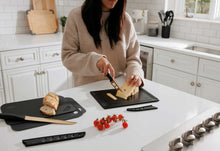 Kitchen knife set in use: slicing bread with black-handled knives and boards