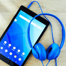 Blue on-ear headphones with wired connection beside a tablet screen