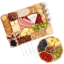 Bamboo cheese board with white-handled knives and compartments for crackers, meat, and fruit