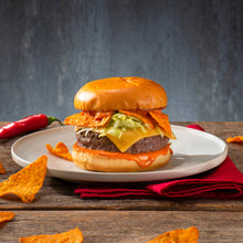 Burger topped with cheese and salsa with tortilla chips on a plate