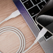 White braided USB-C cable plugged into a tablet port next to a laptop