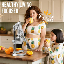 Family using a manual juicer press at a kitchen table with fresh juice glasses