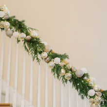 Silver ornament garland with LED lights arranged along a staircase railing