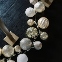 Close-up of silver and white textured ornaments on the LED-lit garland