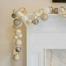 Silver ornament garland with LED lights draped over a mantel