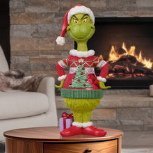 Jim Shore Grinch statue wearing a red Christmas sweater and Santa hat, with a gift at his feet
