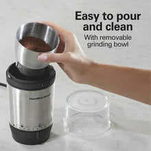 Hand holding removable stainless grinding bowl on an electric coffee grinder