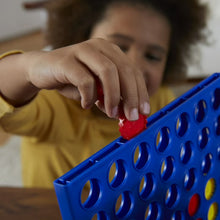 Child placing a red disc into a blue Connect 4 grid game