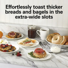 Bagels and toast on plates beside a toaster for extra-wide slots