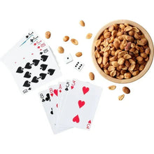 Honey roasted peanuts in a bowl with scattered peanuts and playing cards on white