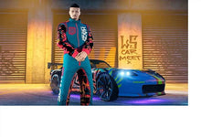 Standing man in a colorful jacket beside a blue sports car under warm lights