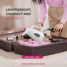Portable handheld garment steamer resting on a compact case, white with pink accents