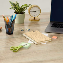 Green Fiskars scissors on desk near notebook and stationery