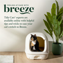 Covered cat litter box with white hood, a calico cat inside, and a green plant nearby.