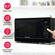 Black countertop microwave oven with digital keypad and hand pressing buttons