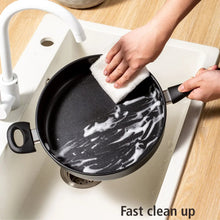 Black non-stick pan being wiped with a cloth, showing easy-clean surface