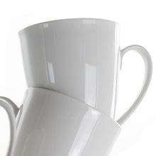 White porcelain mugs overlapping, curved handles and glossy finish, angled close-up