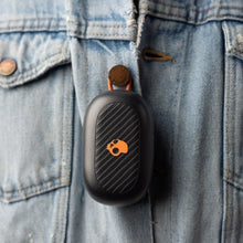 Black earbud with orange skull icon on denim jacket pocket