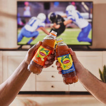 Two hands holding Lipton iced tea bottles outdoors, one labeled Peach