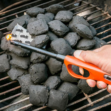 Fire starter cubes on charcoal with orange-handled lighter tool