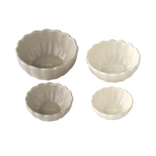 Set of four beige ceramic measuring cups with embossed cup-size markings
