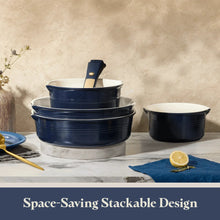 Blue ceramic cookware set with stacked pots, lids, and a frying pan.