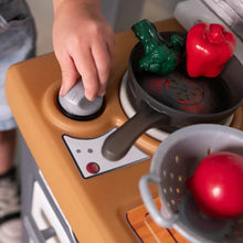Toy stovetop with frying pan and pot over burners, with plastic vegetables